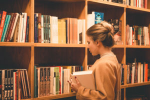 本屋で本を選んでいる金髪の外国人女性